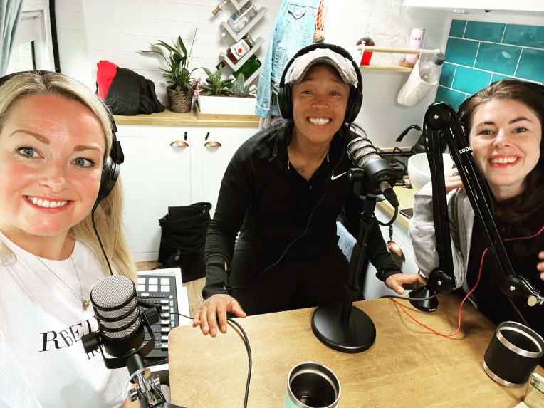 Anna, Teia and Lauren sitting around a table with microphones ready to record a podcast